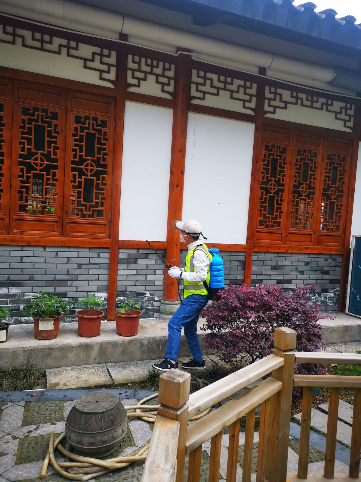 快立克环保四害消杀现场作业实拍:工作人员在建筑门口(靠近灌木)进行作业