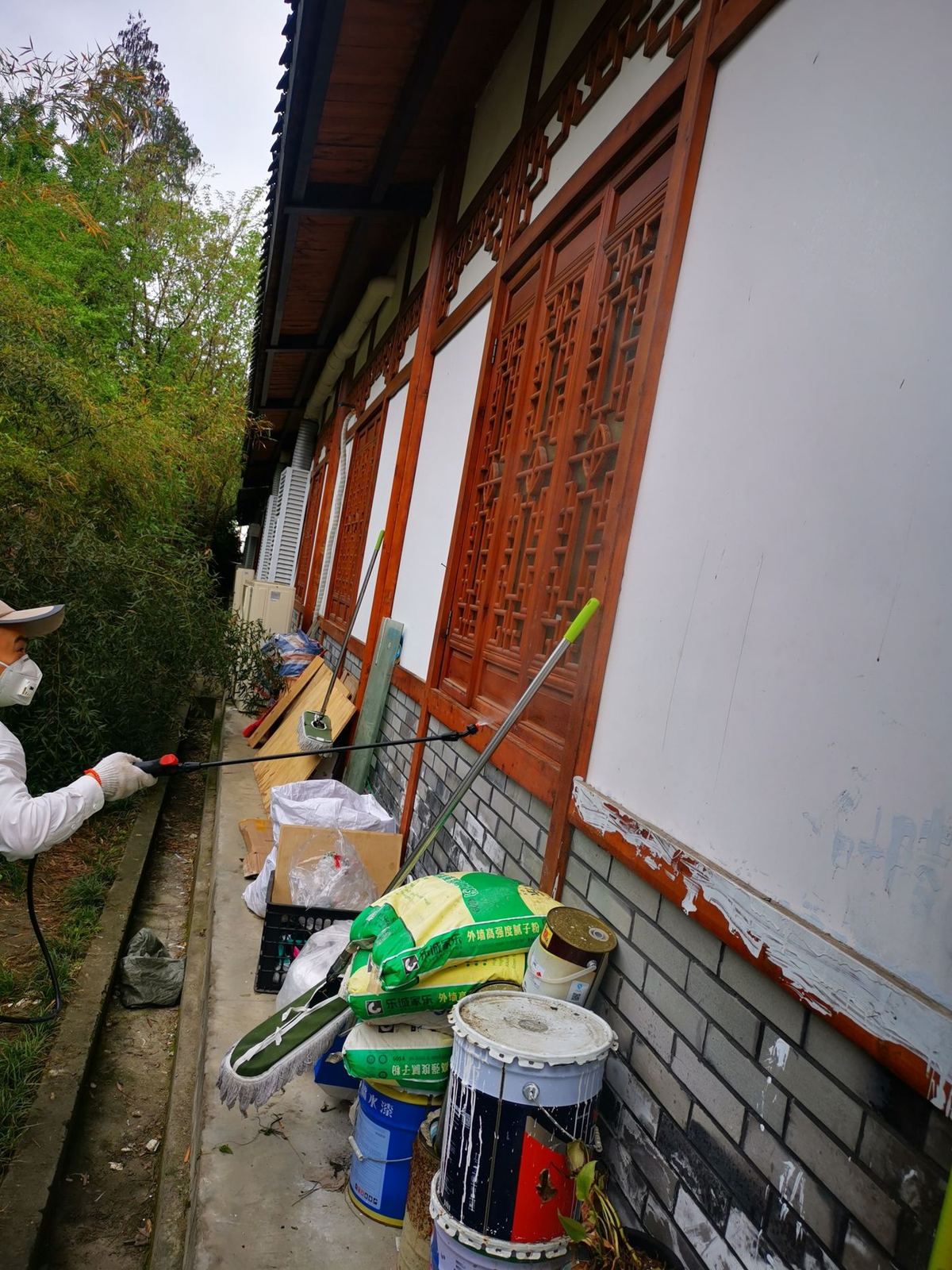 快立克环保四害消杀现场作业实拍:工作人员在建筑角落,操作绿色设备(可能灭虫器械)