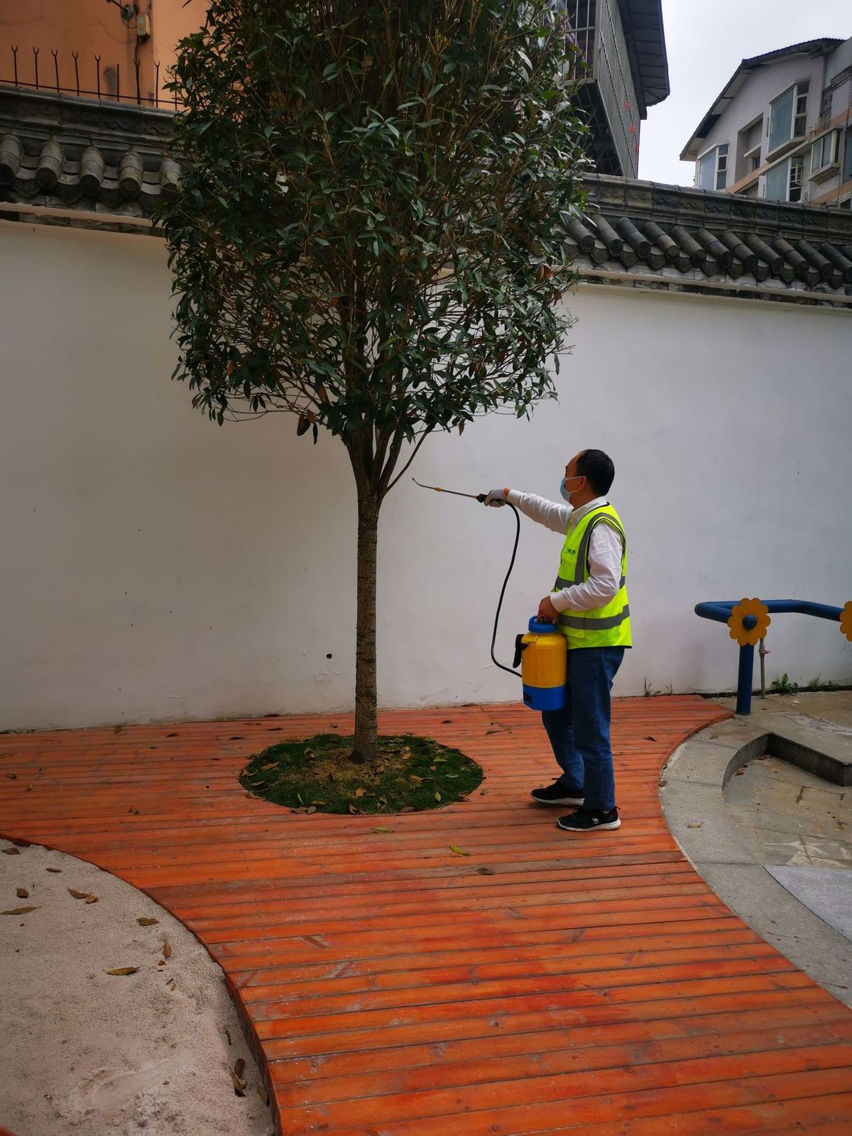 快立克环保四害消杀现场作业实拍：工作人员在庭院中，靠近树木进行作业