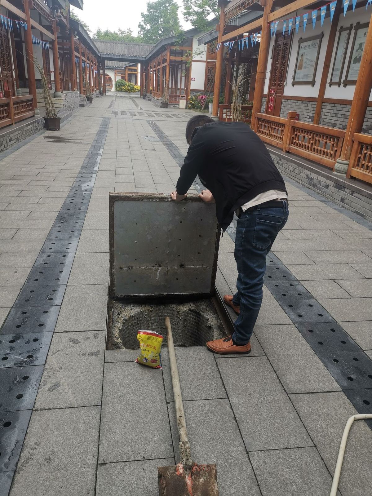 快立克环保环境或建筑现场作业实拍:井盖附近,工作人员操作工具(清理或维护)