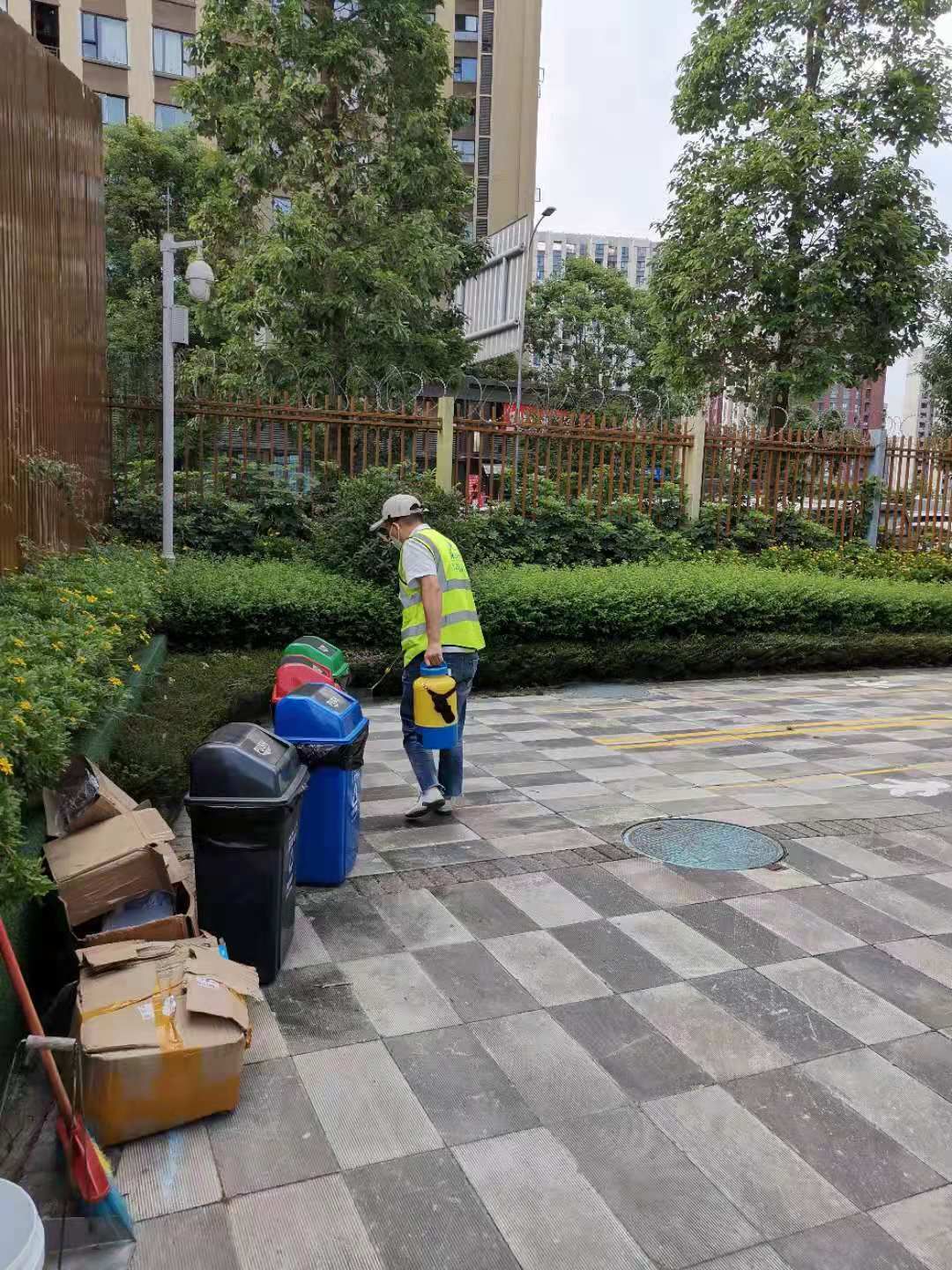 快立克环保环境或建筑现场作业实拍：庭院中工作人员及清洁设备（如垃圾桶、扫帚）